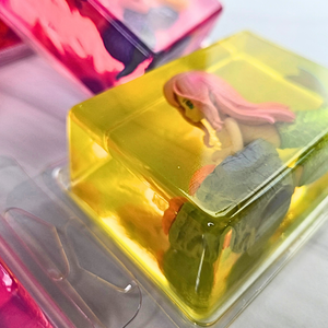 Toy mermaid figure in a clear yellow glycerin soap, in clear packaging on a white background