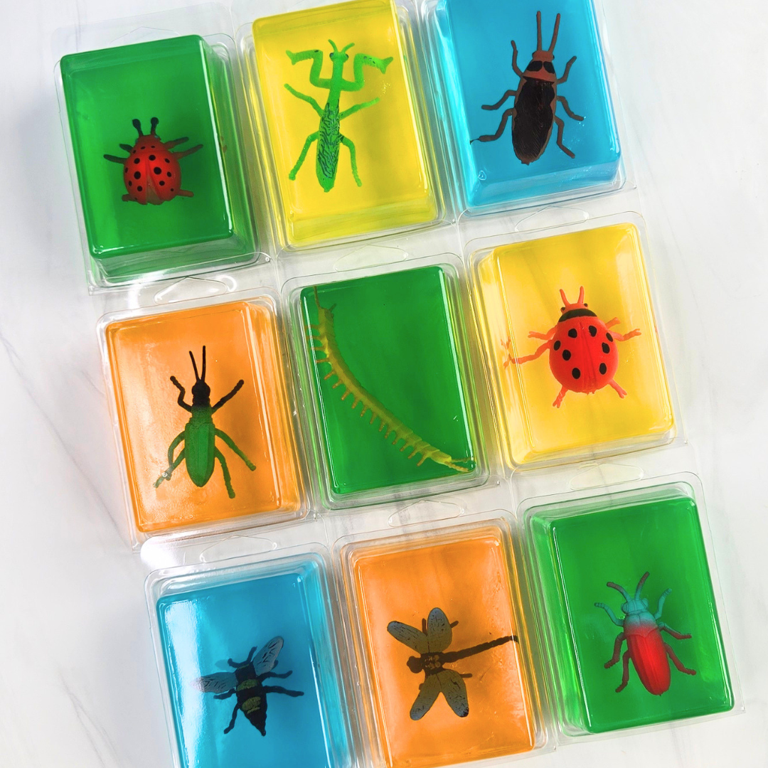 Colorful soap bars with embedded insect toys in clear packaging on a white background