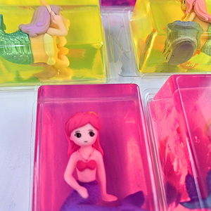 Mermaid figurine in  clear glycerin soap, in plastic packaging on a light gray background