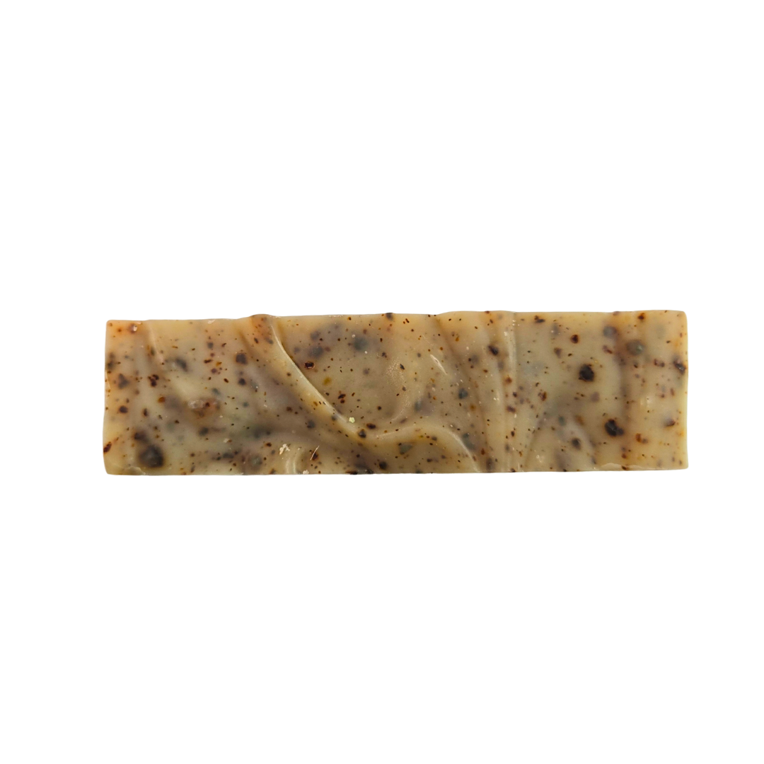 The top of a soap bar with a swirled design. The soap is beige with speckles of persimmon fruit.