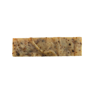 The top of a soap bar with a swirled design. The soap is beige with speckles of persimmon fruit.
