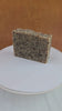 A bar of Persimmon & Pear Shea Magic Soap. The soap is beige with speckles of  dark persimmon fruit shreds. The soap is on a revolving table and the video shows all angles of the soap as it turns.